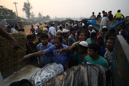 Rohingya refugees gesture to Bangladeshi fish sellers at the dawn fish market in Kutupalong refugee camp in Cox's Bazaar, Bangladesh, March 27, 2018. REUTERS/Clodagh Kilcoyne