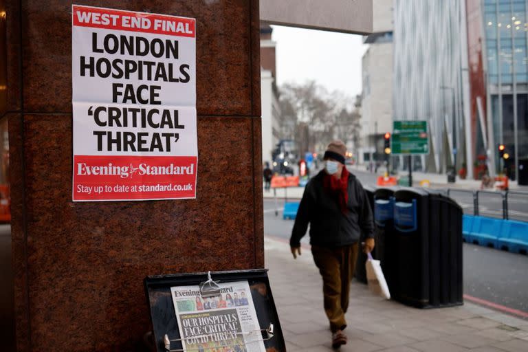 Un peatón con una mascarilla pasa frente a un puesto de los periódicos Evening Standard en el centro de Londres el 8 de enero de 2021. El sistema sanitario inglés está al borde del colapso