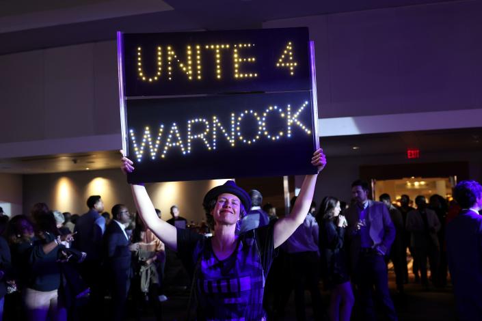 Athena Soules holds a sign as she attends an election night watch party for Sen. Raphael Warnock (D-GA) on December 6, 2022 in Atlanta, Georgia. Sen. Warnock is competing today in a runoff election against his Republican challenger Herschel Walker.
