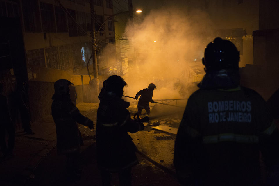 Firefighters put out a burning barricade during clashes at the Pavao Pavaozinho slum in Rio de Janeiro, Brazil, Tuesday, April 22, 2014. Intense exchanges of gunfire, numerous blazes set alit and a shower of homemade explosives and glass bottles onto a busy avenue in Rio de Janeiro’s main tourist zone erupted Tuesday night after the death of a popular young shantytown resident. (AP Photo/Felipe Dana)