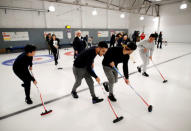 A refugee family from Afghanistan walk up the ice as they are introduced to the sport of curling at the Royal Canadian Curling Club during an event put on by the "Together Project", in Toronto, March 15, 2017. REUTERS/Mark Blinch