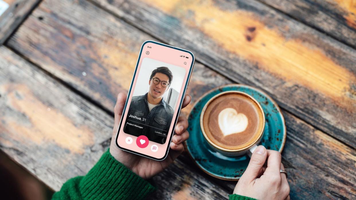 elevated view of young woman looking for love with online dating app on smartphone while drinking coffee