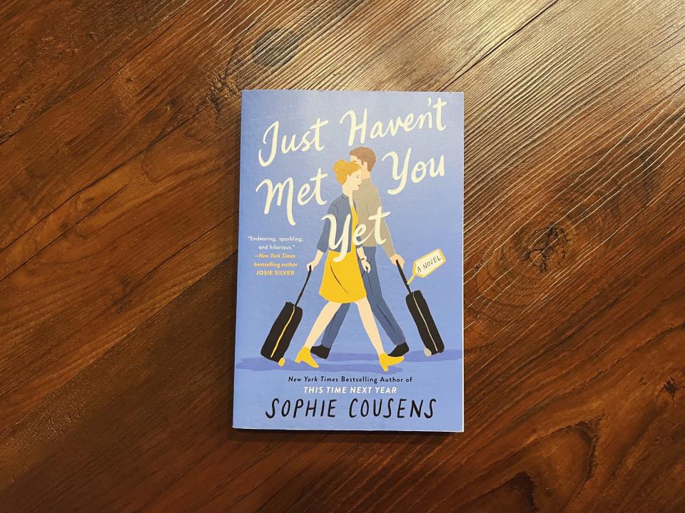 Book cover of "Just Haven't Met You Yet" by Sophie Cousens, featuring illustrated woman walking with luggage