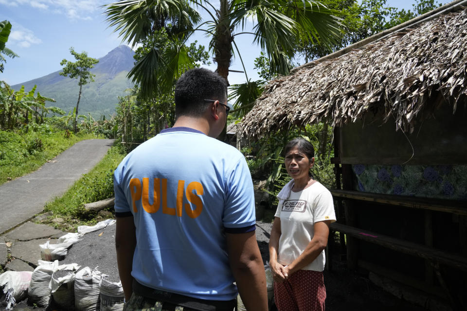 A policeman asks a resident inside the "permanent danger zone" near Mayon volcano to leave the area as they check for evacuees returning or still staying at their homes at Calbayog village in Malilipot town, Albay province, northeastern Philippines, Thursday, June 15, 2023. Thousands of residents have left the mostly poor farming communities within a 6-kilometer (3.7-mile) radius of Mayon's crater in forced evacuations since volcanic activity spiked last week. (AP Photo/Aaron Favila)