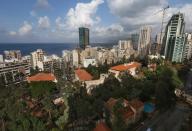 In this February 25, 2014 photo, old buildings with traditional red brick roofs, foreground are overshadowed by newly-constructed modern, tall buildings, in Beirut, Lebanon. One by one, the old traditional houses of Beirut are vanishing as luxury towers sprout up on every corner, altering the city's skyline almost beyond recognition amid an ongoing construction frenzy seemingly immune to tensions from the civil war raging next door. (AP Photo/Hussein Malla)