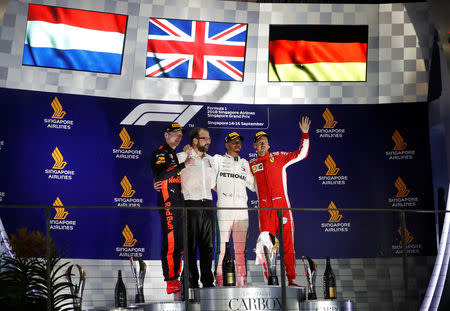 Motor Racing - Formula One - F1 Singapore Grand Prix 2018 - Singapore - September 16, 2018 Mercedes' Lewis Hamilton celebrates on theÊpodiumÊafter winning the race alongside second placed Red Bull's Max Verstappen and third placed Ferrari's Sebastian Vettel REUTERS/Kim Hong-Ji