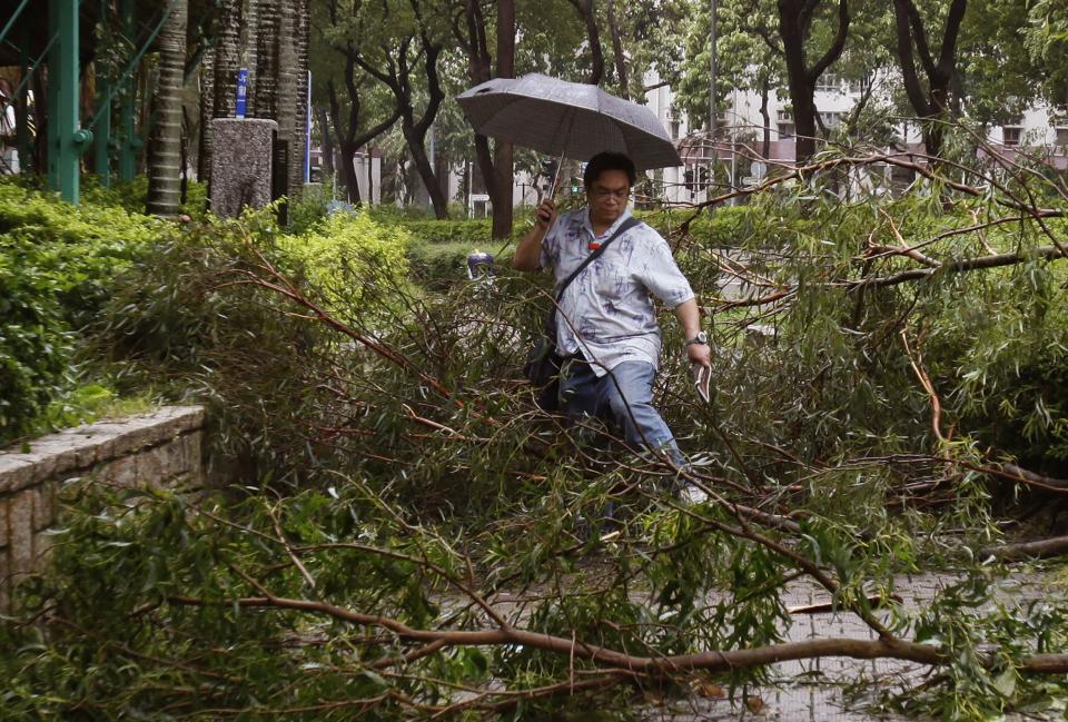 A man walks over fallen branches on a pavement at a residential district after Typhoon Usagi hit Hong Kong