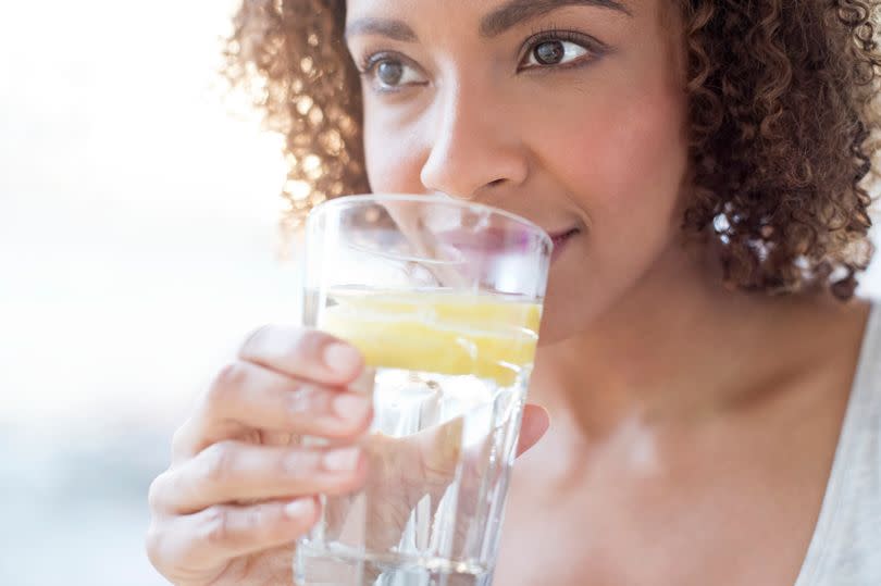 Mid adult woman drinking water with a slice of lemon