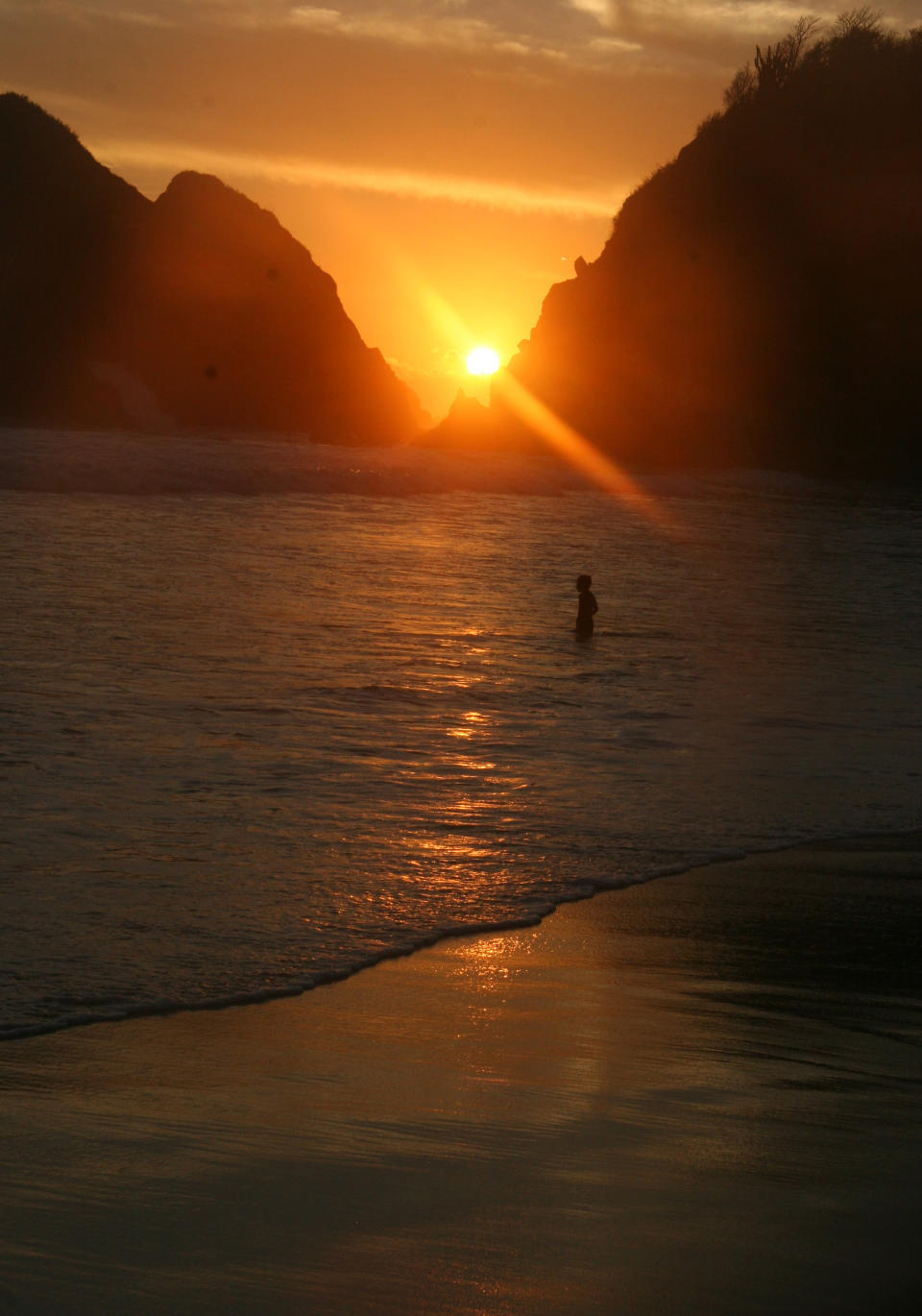 This Jan. 5, 2013 photo shows a lone swimmer wading into the surf during sunset in Zipolite, Mexico. A sleepy town with one main street and no ATMs, Zipolite is one many tiny coastal pueblos that dot the Pacific in Mexico's Southern state of Oaxaca. Watching the brilliant sunsets from the beach is a nightly tradition for visitors in this tiny coastal town. (AP Photo/Jody Kurash)