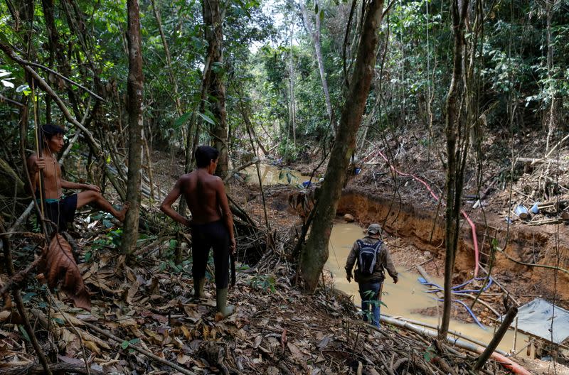 FILE PHOTO: Yanomami indians follow agents of Brazil's environmental agency in a gold mine during an operation against illegal gold mining on indigenous land, in the heart of the Amazon rainforest