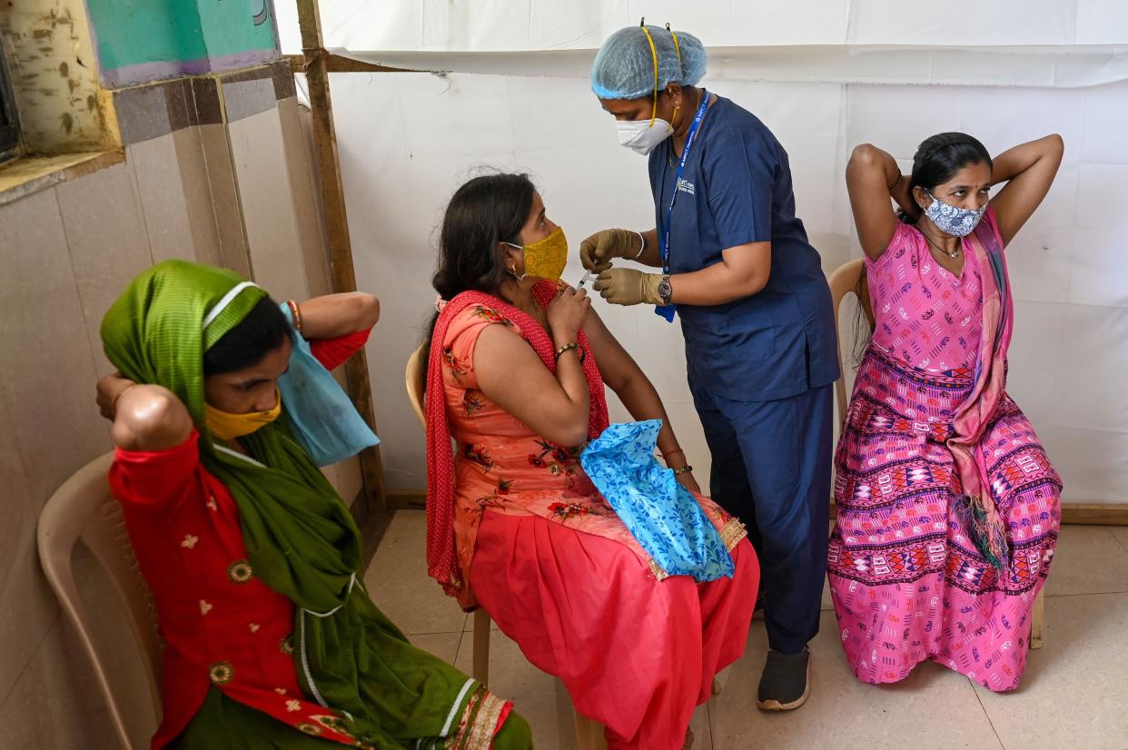 A health worker inoculates a woman with a dose of the Covishield vaccine against the coronavirus at a vaccination center in Mumbai, India on Aug. 12, 2021.