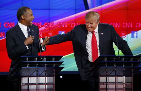 Republican U.S. presidential candidate businessman Donald Trump (R) reacts to a comment from Dr. Ben Carson (L) and reaches over to him in the midst of the Republican presidential debate in Las Vegas, Nevada December 15, 2015. REUTERS/Mike Blake