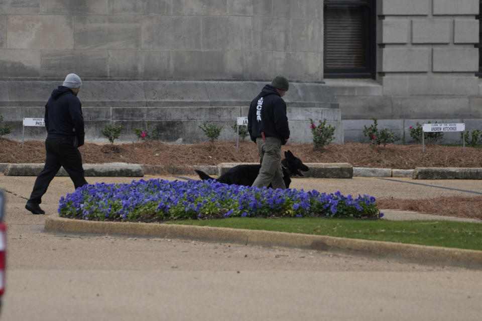 An ordinance sniffing dog patrols the Mississippi State Capitol grounds as Capitol Police respond to a bomb threat at the state building in Jackson, Miss., Wednesday morning, Jan. 3, 2024. The structure was emptied and the grounds cleared of vehicles as officers investigated. (AP Photo/Rogelio V. Solis)