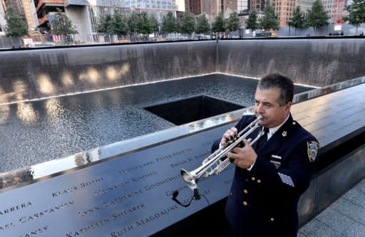 Un policía neoyorquino practica con la trompeta junto al monumento en honor de la Torre Sur del World Trade Center antes de participar en las ceremonias por el 11 aniversario de los atentados del 11 de septiemmbre de 2001, este martes en Nueva York. (AFP/Pool | Justin Lane)