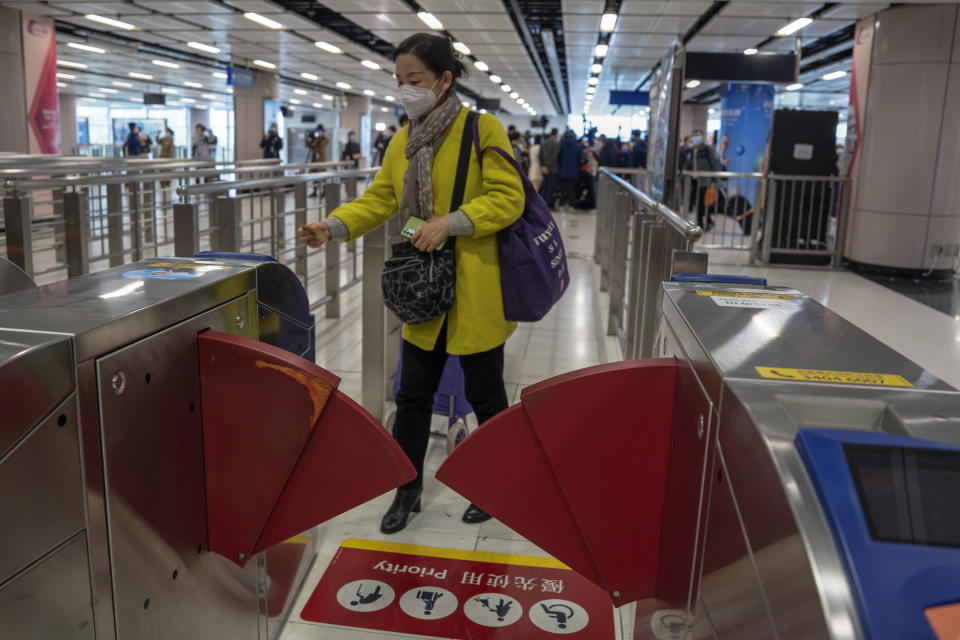 A woman wearing a face mask enters a gate at the departure hall at Lok Ma Chau station following the reopening of crossing border with mainland China, in Hong Kong, Sunday, Jan. 8, 2023. Travelers crossing between Hong Kong and mainland China, however, are still required to show a negative COVID-19 test taken within the last 48 hours, a measure China has protested when imposed by other countries. (AP Photo/Bertha Wang)