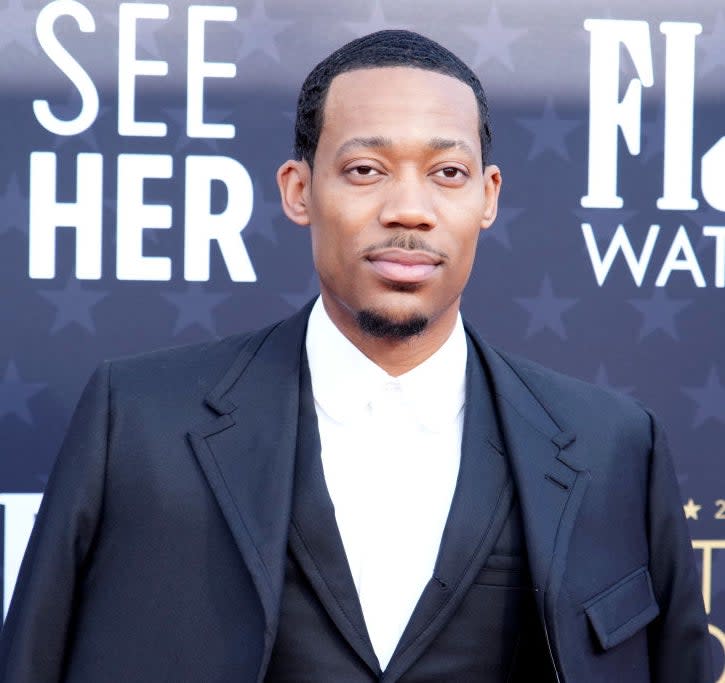 Tyler James Williams at the Critics Choice Awards, wearing a black suit with a black tie and white shirt