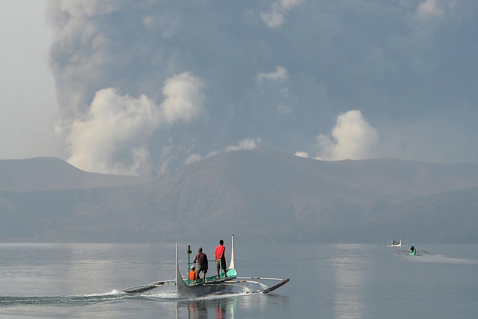 Residents living at the foot of Taal volcano ride outrigger canoes to reach their homes while the volcano spews ash as seen from Tanauan town in Batangas province, south of Manila, on January 13, 2020. (Photo by Ted ALJIBE / AFP) (Photo by TED ALJIBE/AFP via Getty Images)