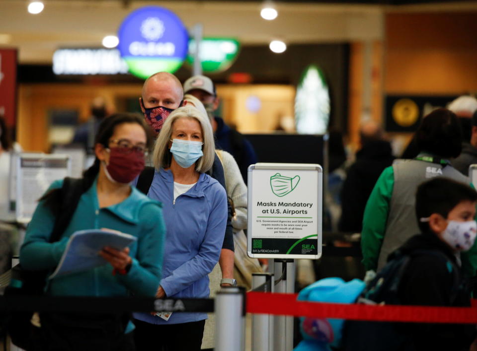 Airline travelers wait in line at a security checkpoint at Seattle-Tacoma International Airport in SeaTac, Washington, April 12, 2021.  REUTERS/Lindsey Wasson