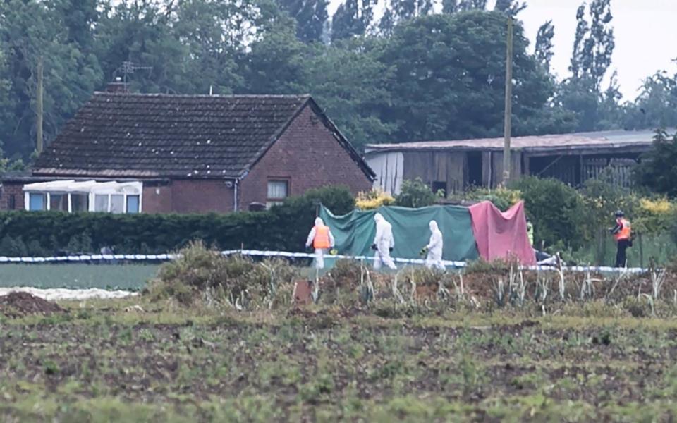 Police in hazmats enter the tent covering the crash site