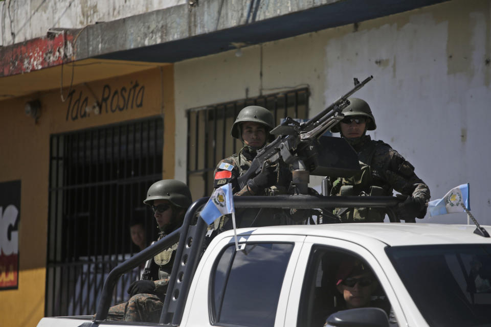 Heavily armed soldiers ride a vehicle that escorts the caravan of Guatemalan President Jimmy Morales, as they arrive to a inaugurate a soccer field in Mixco, Guatemala, Monday, Sept. 17, 2018. Morales' government will defy a ruling by the country's top court and block the return of Ivan Velasquez, who is leading a U.N.-backed anti-corruption commission. (AP Photo/Moises Castillo)