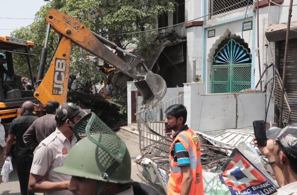 A bulldozer dismantles structures outside a mosque during the demolition drive of illegal structures in Delhi’s violence-hit Jahangirpuri (EPA)