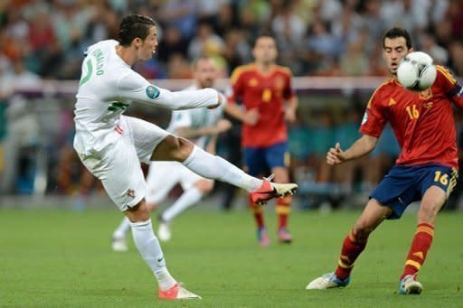 Portugal forward Cristiano Ronaldo (left) kicks the ball towards goal as Spain midfielder Sergio Busquets looks on during the Euro 2012 semi-final at the Donbass Arena in Donetsk, Ukraine
