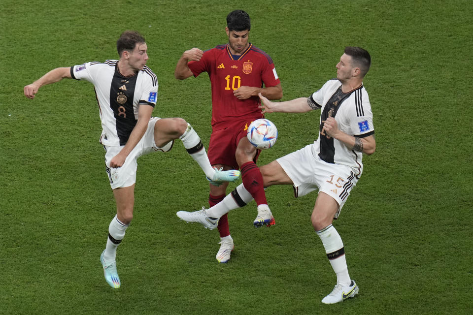 Spain's Marcos Asensio, centre, challenges for the ball with Germany's Leon Gorentzka, left, and Germany's Niklas Suele during the World Cup group E soccer match between Spain and Germany, at the Al Bayt Stadium in Al Khor, Qatar, Sunday, Nov. 27, 2022. (AP Photo/Ricardo Mazalan)