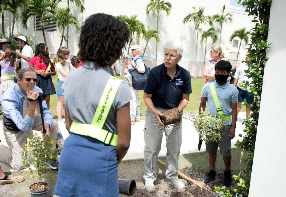 Susan Lerner, horticulturalist for the Preservation Foundation of Palm Beach, helps students plant native partridge pea plants during Earth Day festivities on April 22 at the Mandel Recreation Center.