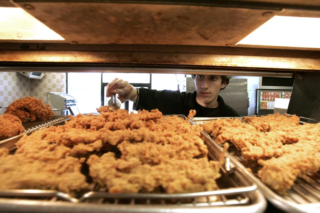 Nick Gamble reaches for a piece of chicken while working at the Kentucky Fried Chicken store.