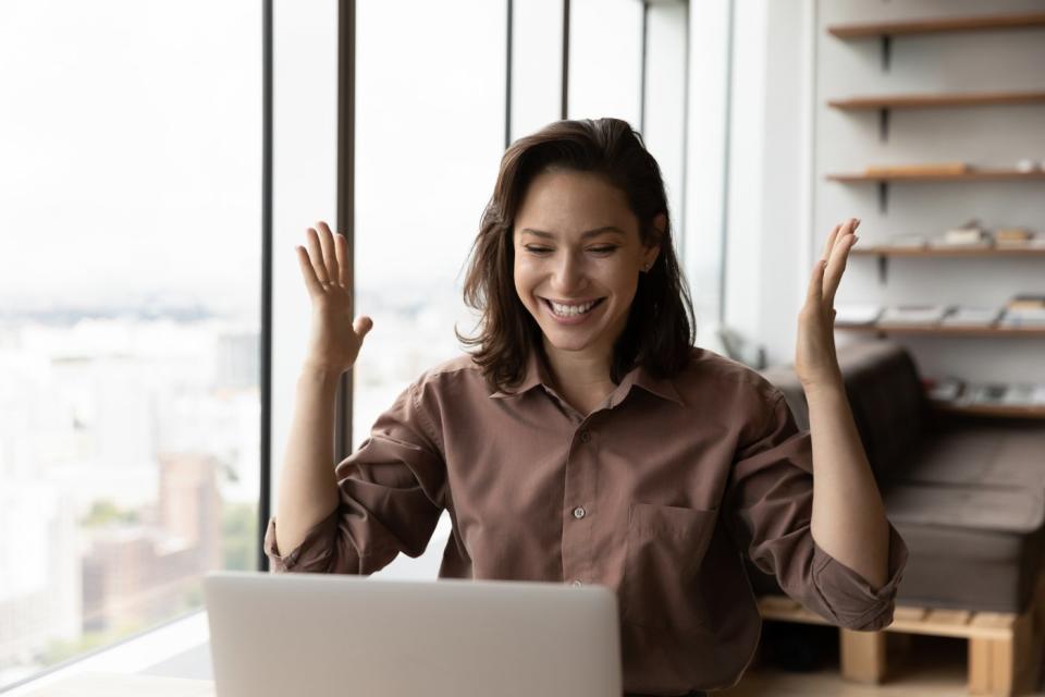 An investor smiles and looks at something on a laptop in an office.