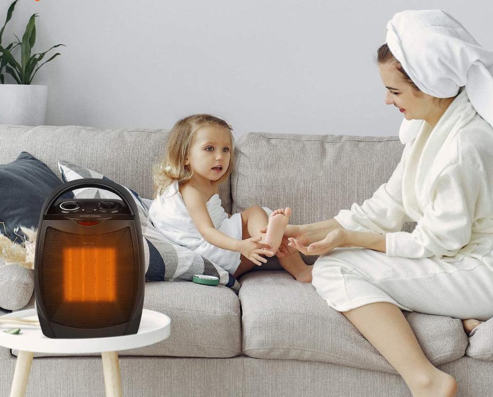 Mother wearing a robe and towel on her head with a toddler girl on the couch, a space heater in front of them.