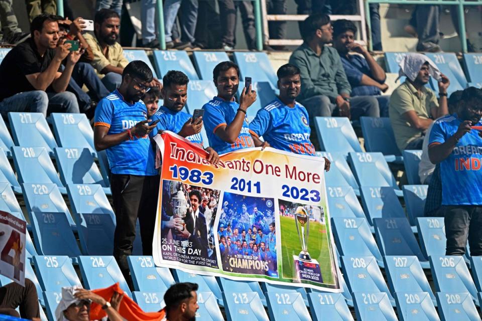 Indian fans hold a poster as they watch the 2023 ICC Men’s Cricket World Cup one-day international (ODI) match between Australia and South Africa on 12 October  (AFP via Getty Images)