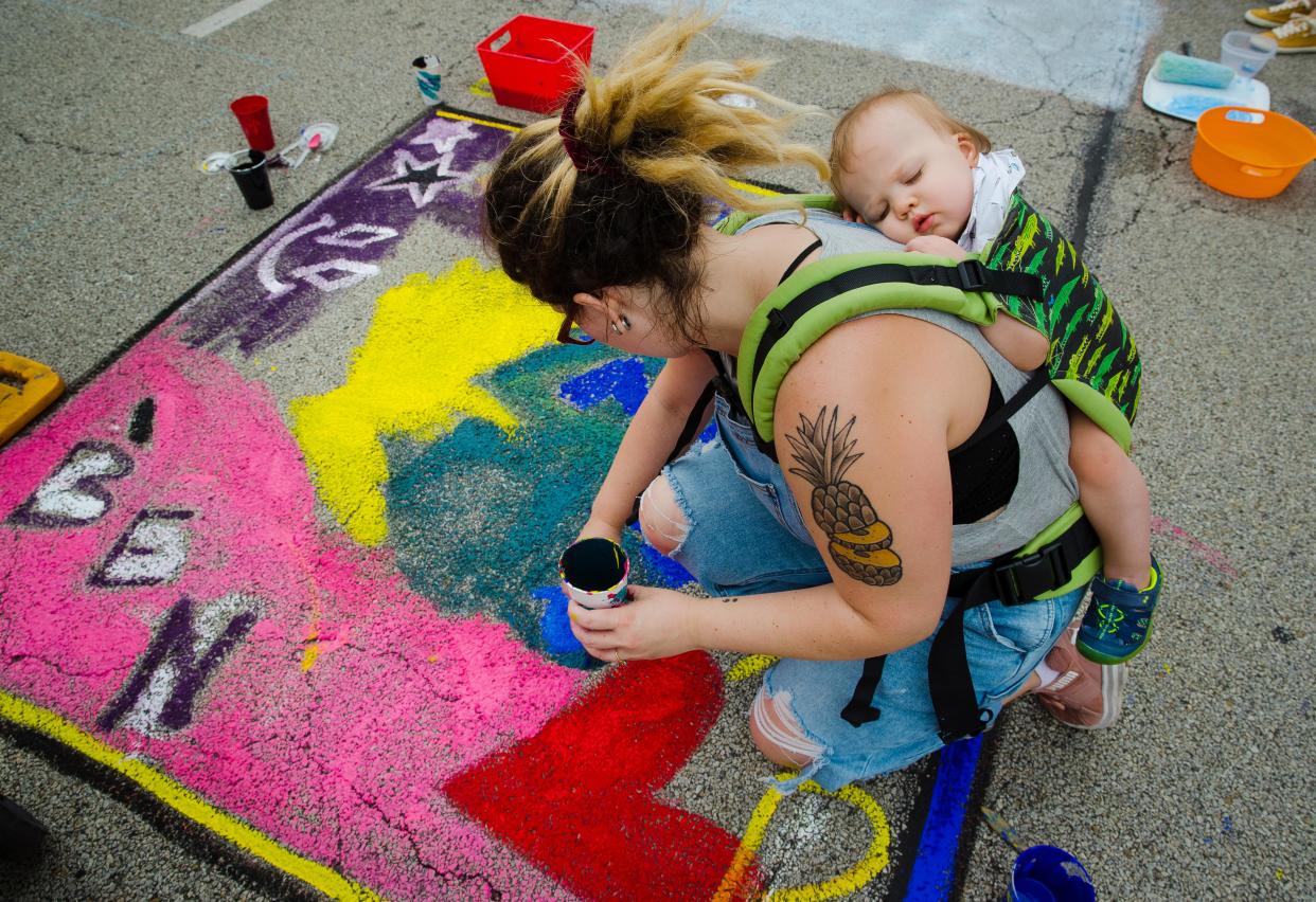 Rachel Morrison's 1-year-old son Benjamin sleeps while nestled in a carrier on her back during the Springfield Art Association's 2019 Paint the Street event in downtown Springfield on June 22, 2019. Morrison said painting was much harder while carrying her 20-pound son.