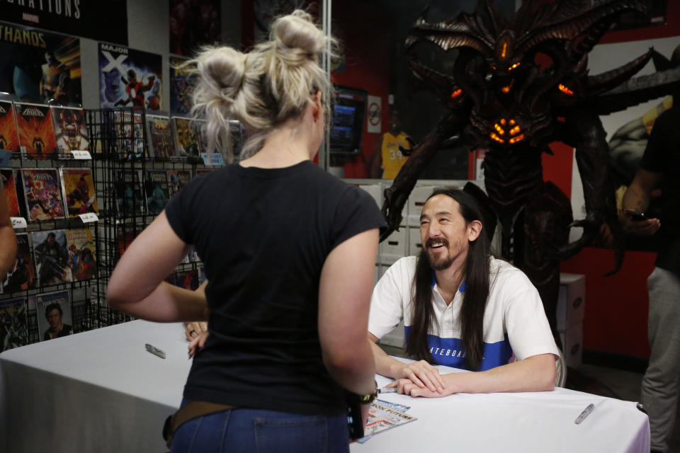 Steve Aoki talks to a fan during a comic book signing of his new "Neon Future" comic book series at Multiverse Corps. Comics on Thursday, May 2, 2019, in Miami. (AP Photo/Brynn Anderson)