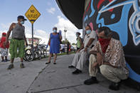 People, social distancing and wearing masks to prevent the spread of the new coronavirus, chat as they wait in line at a mask distribution event, Friday, June 26, 2020, in a COVID-19 hotspot of the Little Havana neighborhood of Miami. Florida banned alcohol consumption at its bars Friday as its daily confirmed coronavirus cases neared 9,000, a new record that is almost double the previous mark set just two days ago. (AP Photo/Wilfredo Lee)