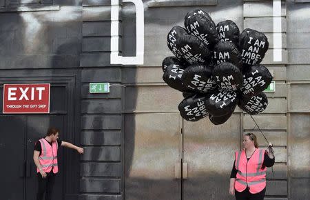 A woman holds balloons at 'Dismaland', a theme park-styled art installation by British artist Banksy, at Weston-Super-Mare in southwest England, Britain, August 20, 2015. REUTERS/Toby Melville