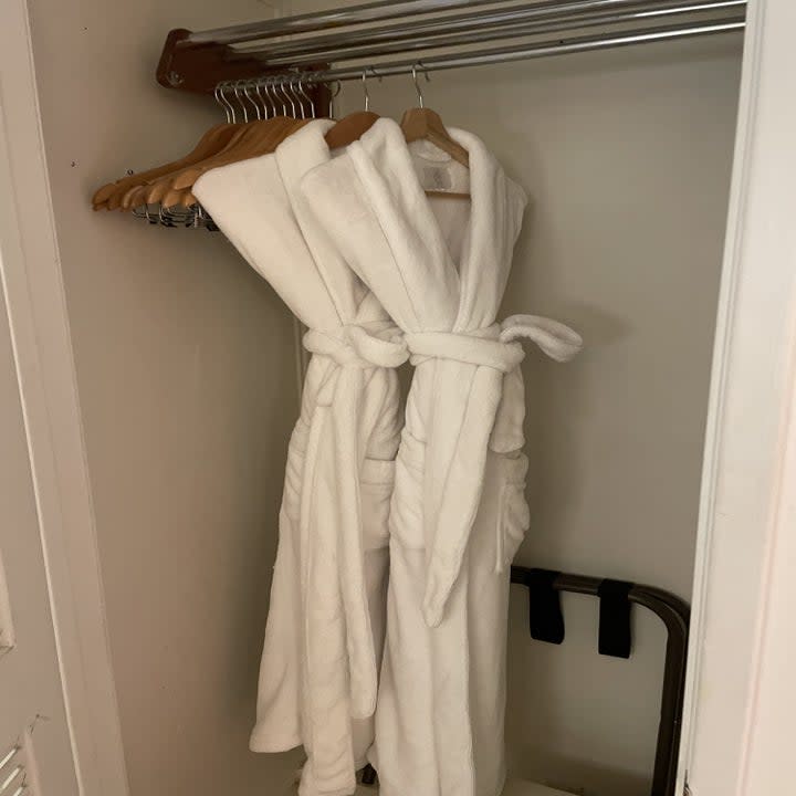 Two robes hanging in the hotel room closet