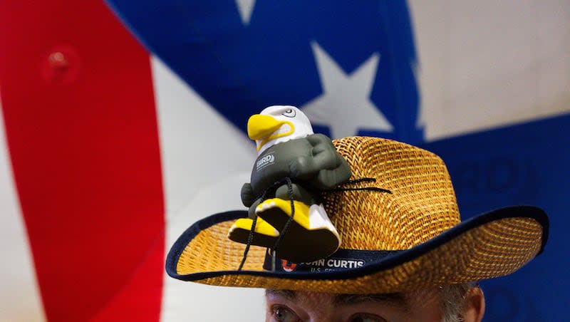 Gil Allis, a volunteer for JR Bird, running for the 3rd Congressional District, and John Curtis, running for U.S. Senate, wears a Curtis hat with a bald eagle with Bird’s name tied to it during the Utah Republican Party state nominating convention at the Salt Palace Convention Center in Salt Lake City on Saturday, April 27, 2024.