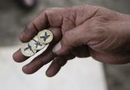 A gambler shows coins used in a local illegal game called "Kara Y Kruz" in Quezon City, Metro Manila, Philippines February 21, 2015. When paying your final respects for a relative or friend, the last thing you might expect to see at the wake is people placing bets on a card game or bingo. Not in the Philippines. Filipinos, like many Asians, love their gambling. But making wagers on games such as "sakla", the local version of Spanish tarot cards, is particularly common at wakes because the family of the deceased gets a share of the winnings to help cover funeral expenses. Authorities have sought to regulate betting but illegal games persist, with men and women, rich and poor, betting on anything from cockfighting to the Basque hard-rubber ball game of jai-alai, basketball to spider races. Many told Reuters photographer Erik De Castro that gambling is only an entertaining diversion in a country where two-fifths of the population live on $2 a day. But he found that some gamble every day. Casino security personnel told of customers begging to be banned from the premises, while a financier who lends gamblers money at high interest described the dozens of vehicles and wads of land titles given as collateral by those hoping lady luck would bring them riches. REUTERS/Erik De Castro TPX IMAGES OF THE FDAY PICTURE 29 OF 29 FOR WIDER IMAGE STORY "HIGH STAKES IN MANILA". SEARCH "BINGO ERIK" FOR ALL IMAGES.