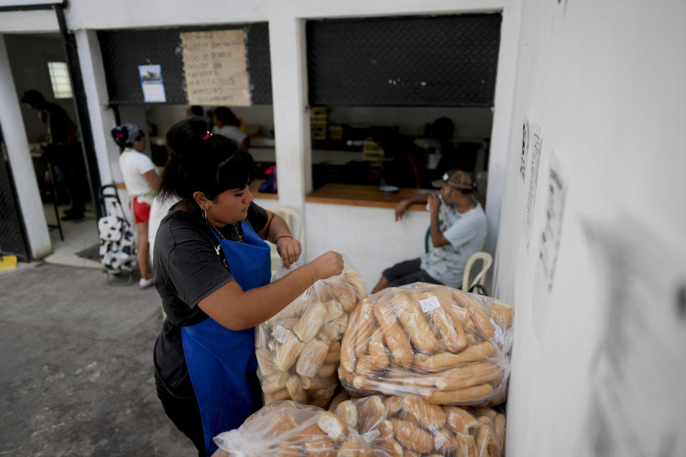 A woman rips open a bag filled with bread to be distributed to neighbors at a soup kitchen, amid rising inflation, in Buenos Aires, Argentina, Thursday, March 16, 2023. (AP Photo/Natacha Pisarenko)