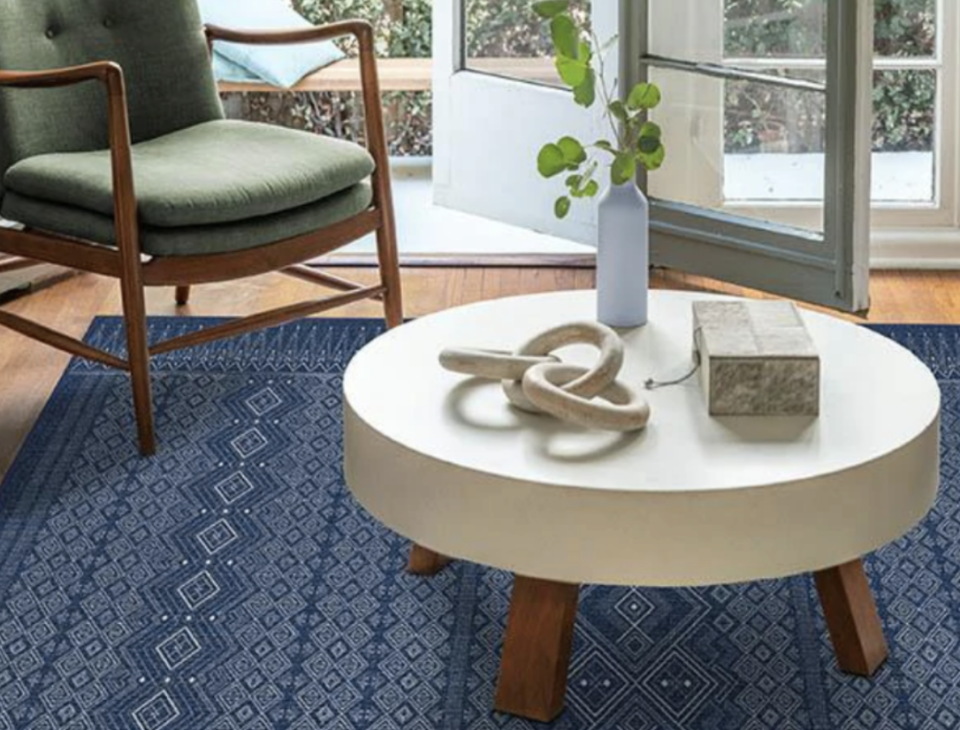 Blue patterned rug with a white coffee table and green chair.