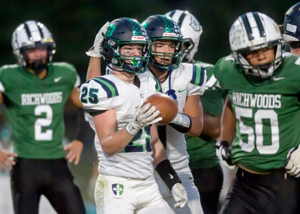 Peoria Notre Dame Ben Mullens pats his teammate Jack Hanley on the helmet after one of Hanley's gains against Richwoods in the first half of their Week 4 football game Friday, Sept. 15, 2023 at Richwoods High School. The Irish routed the Knights 42-7.