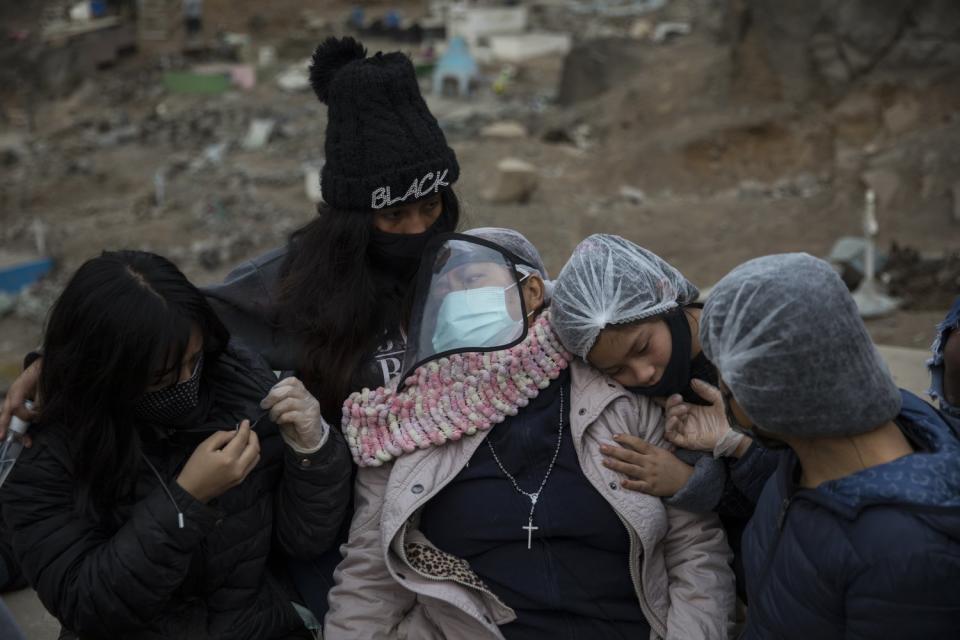 Relatives hug Aurora Davila as she buries her son Ronald Palomo, who died of COVID-19.