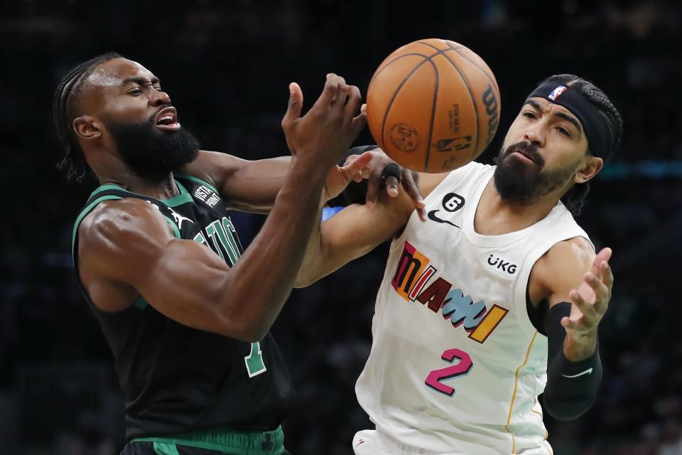 Boston Celtics' Jaylen Brown loses control of the ball next to Miami Heat's Gabe Vincent (2) during the first half of an NBA basketball game Friday, Dec. 2, 2022, in Boston. (AP Photo/Michael Dwyer)
