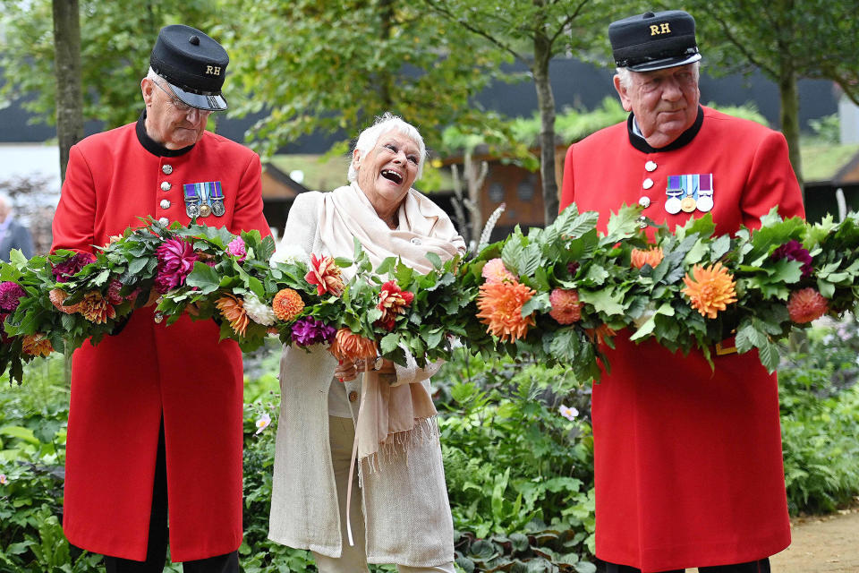 <p>Dame Judi Dench smiles wide as she stands with Chelsea pensioners to open the Queen's Garden display during the 2021<br> RHS Chelsea Flower Show in London on Sept. 20.</p>