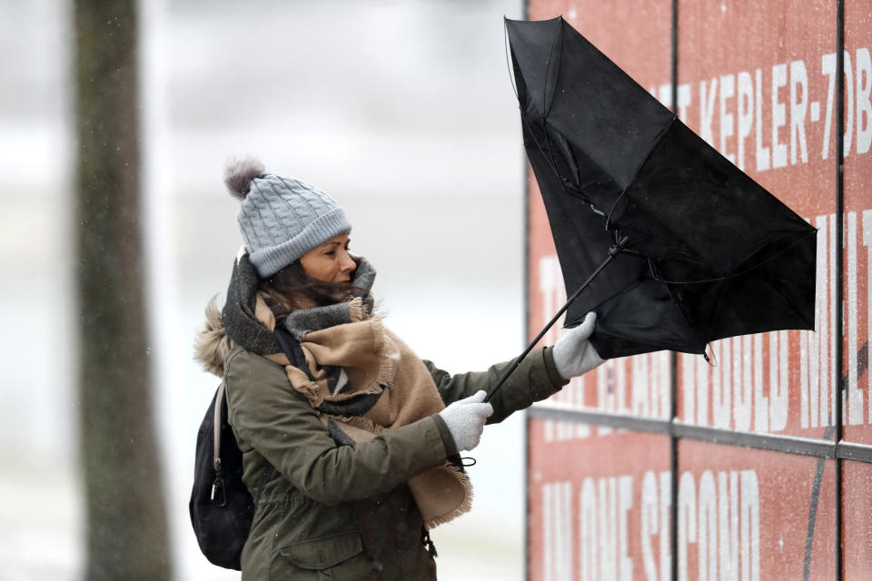 A woman walking the half mile from the Chicago Aquarium to the Adler Planetarium fights a stiff wind inverting her umbrella in the blowing snow off Lake Michigan, Monday, Nov. 11, 2019, in Chicago. (AP Photo/Charles Rex Arbogast)