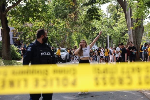 A jubilant reveler is shown behind police tape on Jennings Street. (Jeorge Sadi/CBC - image credit)