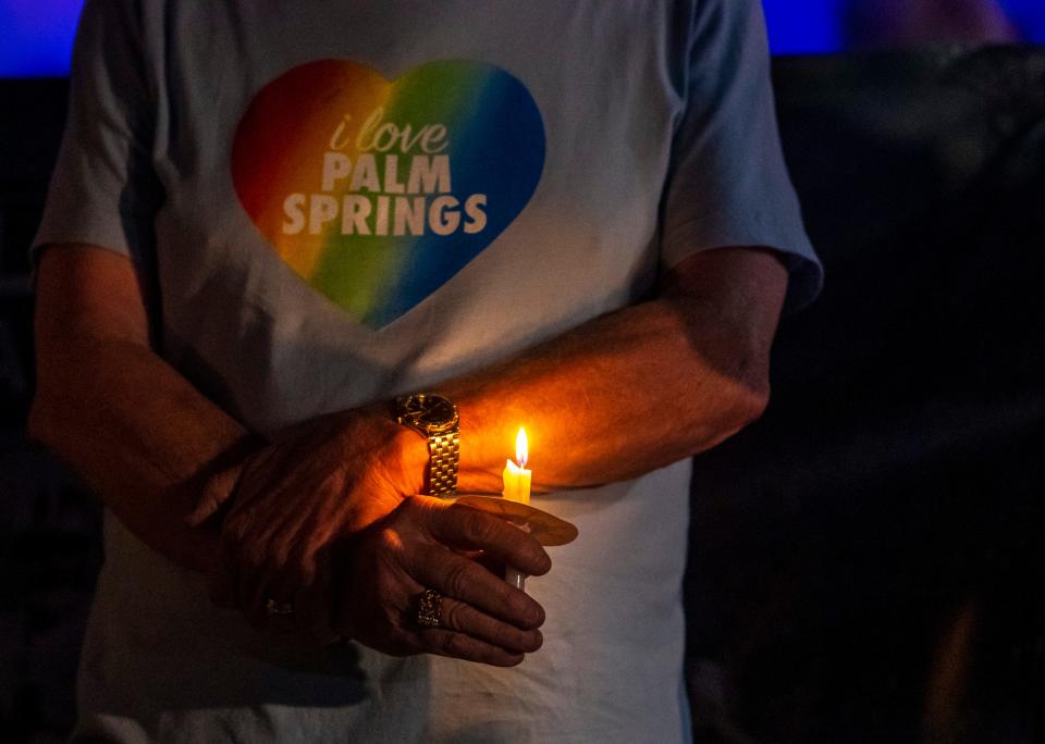 A participant holds a candle close while listening to public leaders speak in response to the Club Q shooting in Colorado Springs during a vigil on Arenas Road in Palm Springs, Calif., Sunday, Nov. 27, 2022. 