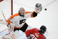 Philadelphia Flyers goaltender Alex Lyon (34) prepares to catch the puck next to Washington Capitals right wing T.J. Oshie (77) during the first period of an NHL hockey game Saturday, May 8, 2021, in Washington. (AP Photo/Nick Wass)