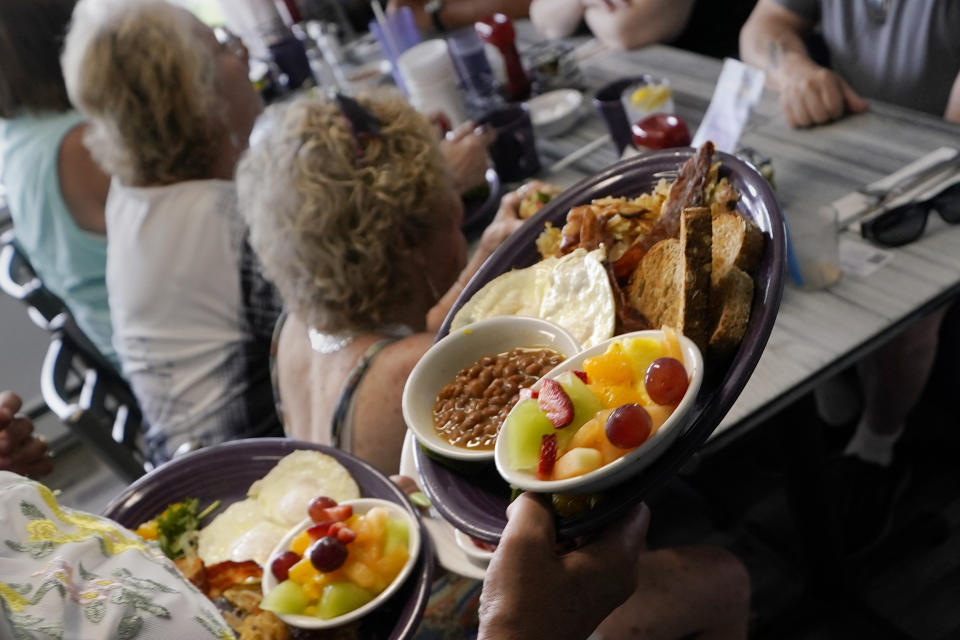 A server carries out a breakfast order for senior citizens participating in the Meals on Wheels "Dine Out Club, at the White Birch Cafe, Wednesday, July 19, 2023, in Goffstown, N.H. Meals on the program meet a dietician-approved one-third of the USDA recommended daily requirements for adults under the federal Older Americans Act Nutrition Program. (AP Photo/Charles Krupa)